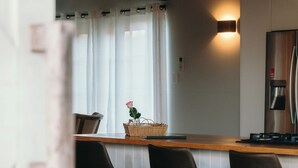 Ett modernt kök med en bänkskiva i trä, barstolar och en kaffemaskin.