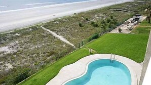 Ein Pool mit Blick auf den Strand und eine Rasenfläche.