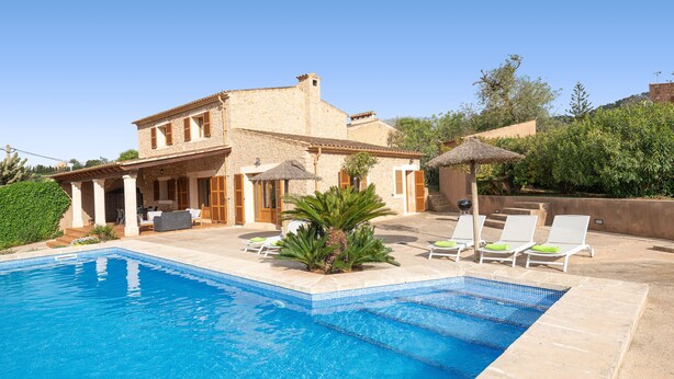 A pool with lounge chairs, a patio area, and a building with a stone facade. - CAS BATLET - Rustic villa with private pool and free Wi-Fi (Felanitx)