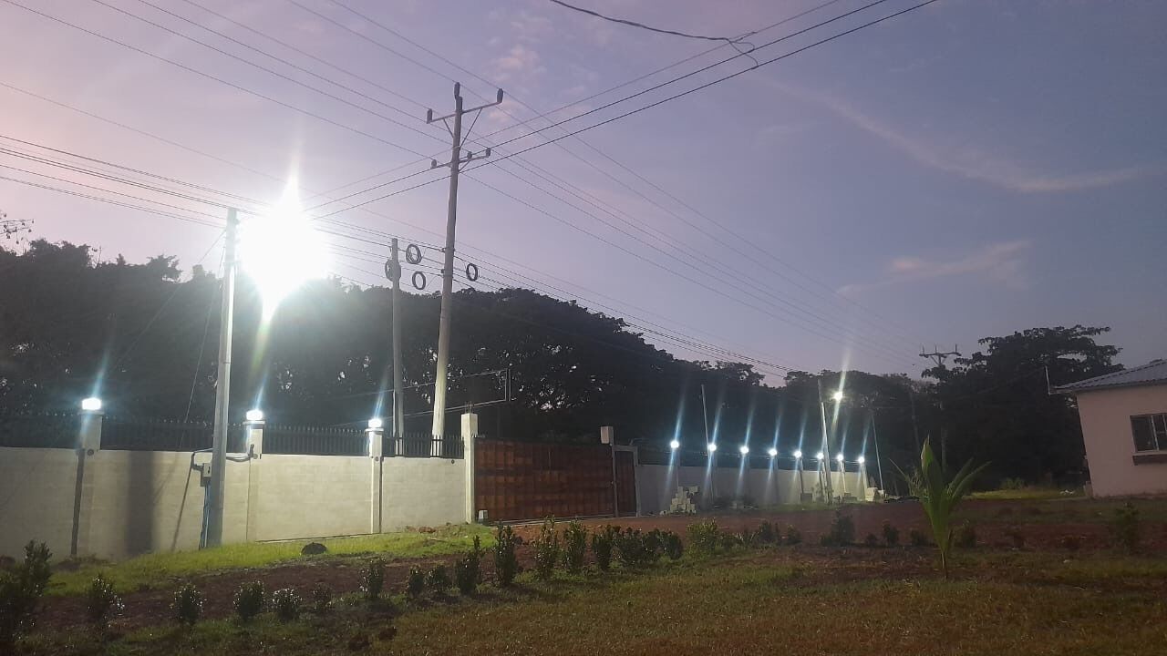 A gated compound with a concrete wall, a metal gate, and a small building.