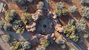 An aerial view of a natural rock formation with a circular clearing surrounded by sparse vegetation. - Cave Dwellers- Zions' Only Hand-sculpted Cave (Fredonia)