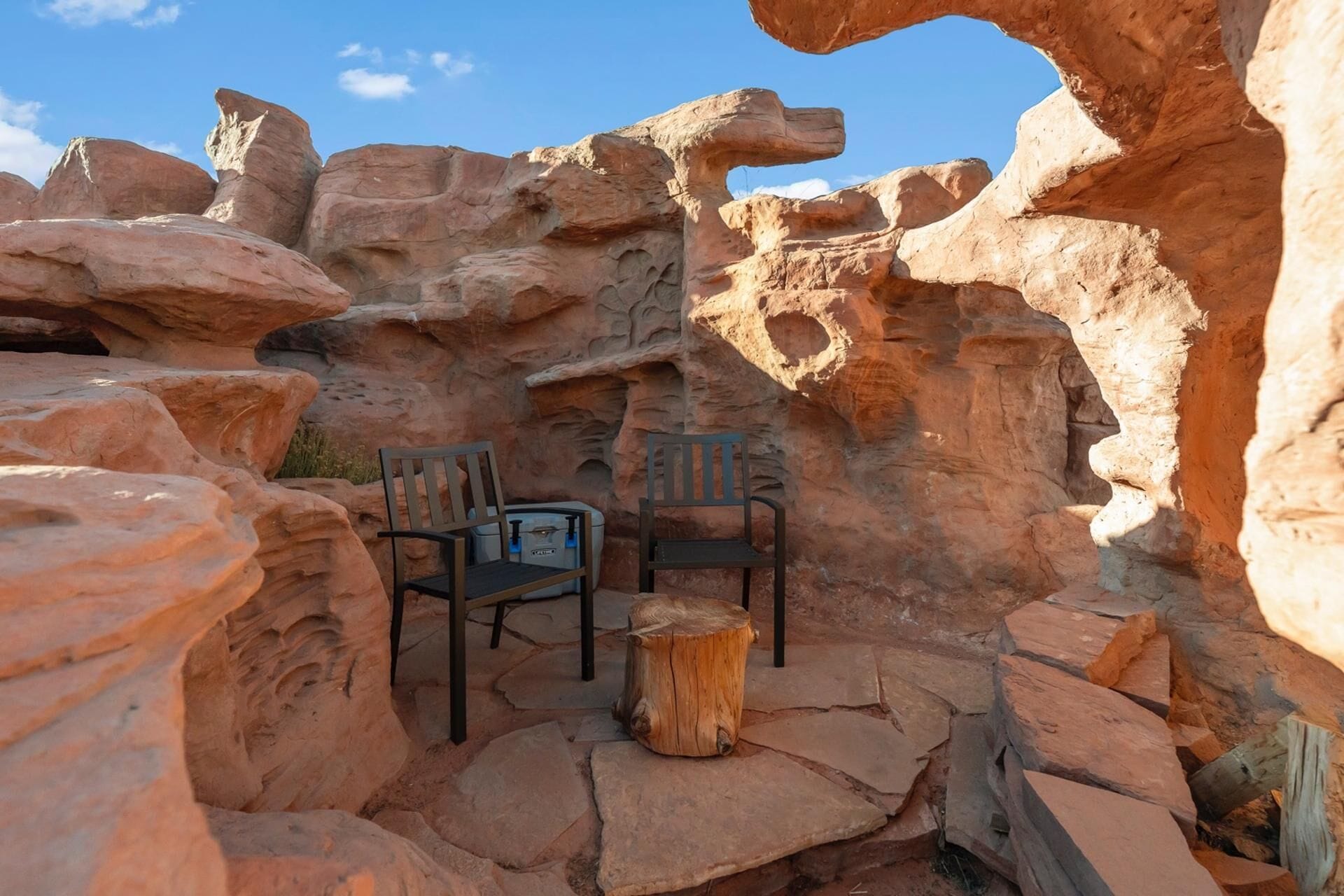 A rock formation with two chairs and a small table, likely a natural rock garden or outdoor seating area.