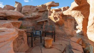 A rock formation with two chairs and a small table, likely a natural rock garden or outdoor seating area.