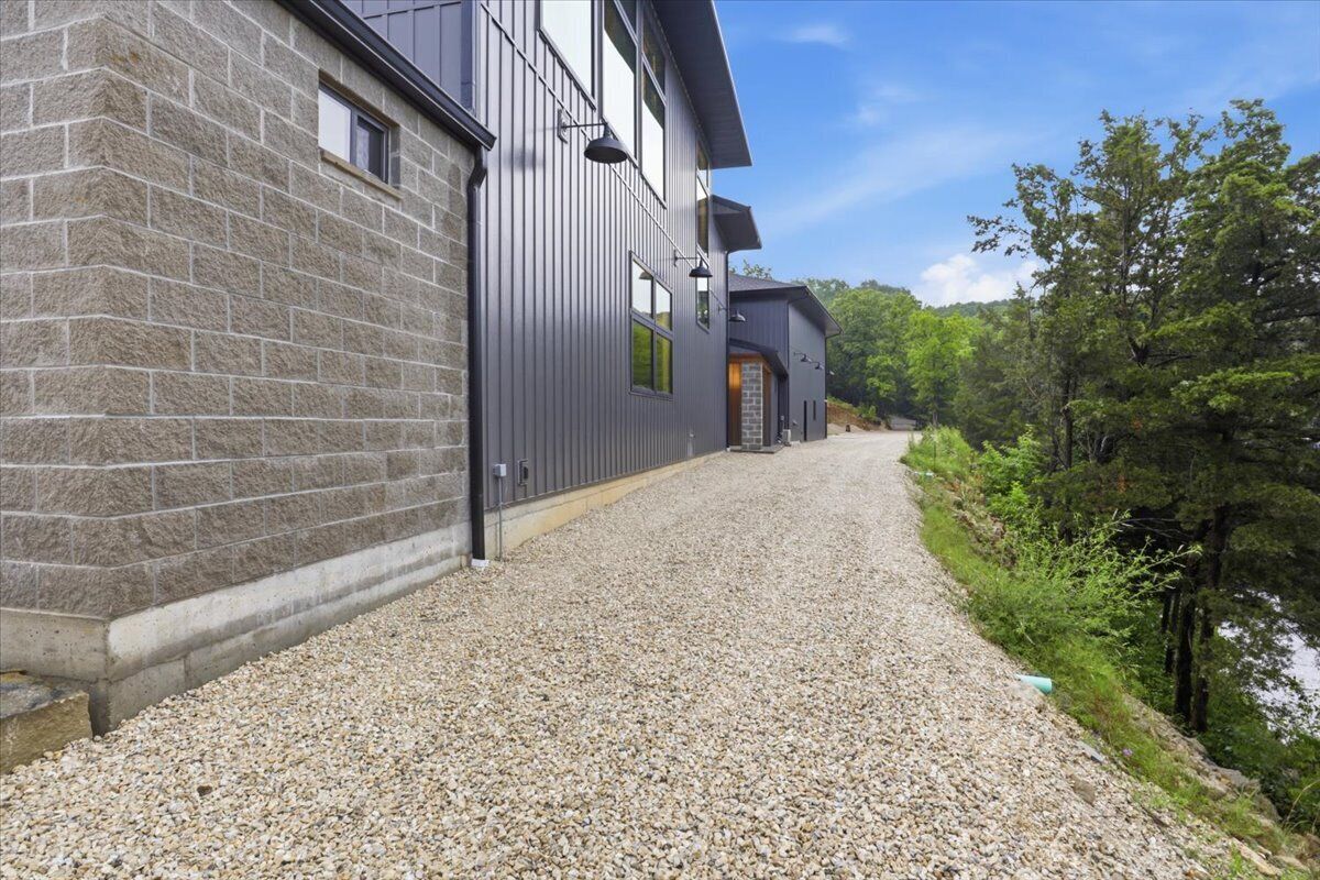 A building with a gravel driveway, stone walls, and a clear sky.