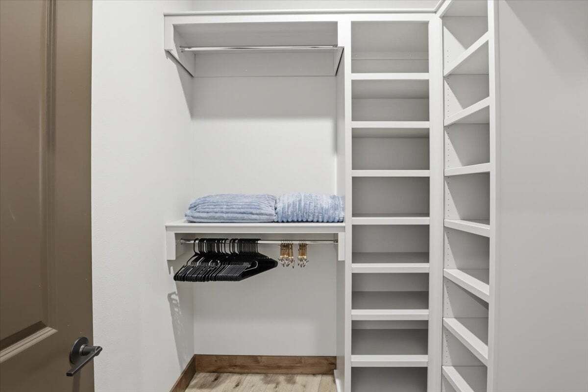A walk-in closet with open shelving, a hanging rod, and a door.
