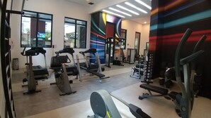 Une salle de sport équipée de tapis de course, de vélos elliptiques et de matériel de musculation.