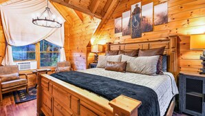A cozy wooden cabin bedroom with a large bed, a wooden headboard, a nightstand, and a window overlooking a forest. - Blackberry Bliss: Pet Friendly, Free Attraction Tixs, Hot Tub, Pool Access, in Pigeon Forge (Pigeon Forge)