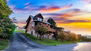 A log cabin with a stone foundation, a porch, and a view of the sunset. - Blackberry Bliss: Pet Friendly, Free Attraction Tixs, Hot Tub, Pool Access, in Pigeon Forge (Pigeon Forge)