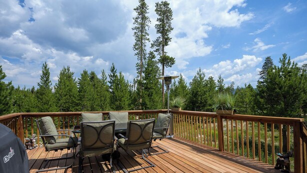 Eine Holzterrasse mit Gartenmöbeln und einem Grill.