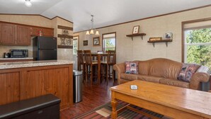 Eine Küche mit Holzausstattung, einem schwarzen Kühlschrank, einer Mikrowelle und einem Essbereich mit Tisch und Stühlen.