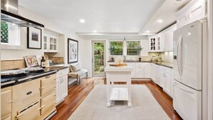 Una cocina moderna con armarios blancos, encimera de madera y una isla central.