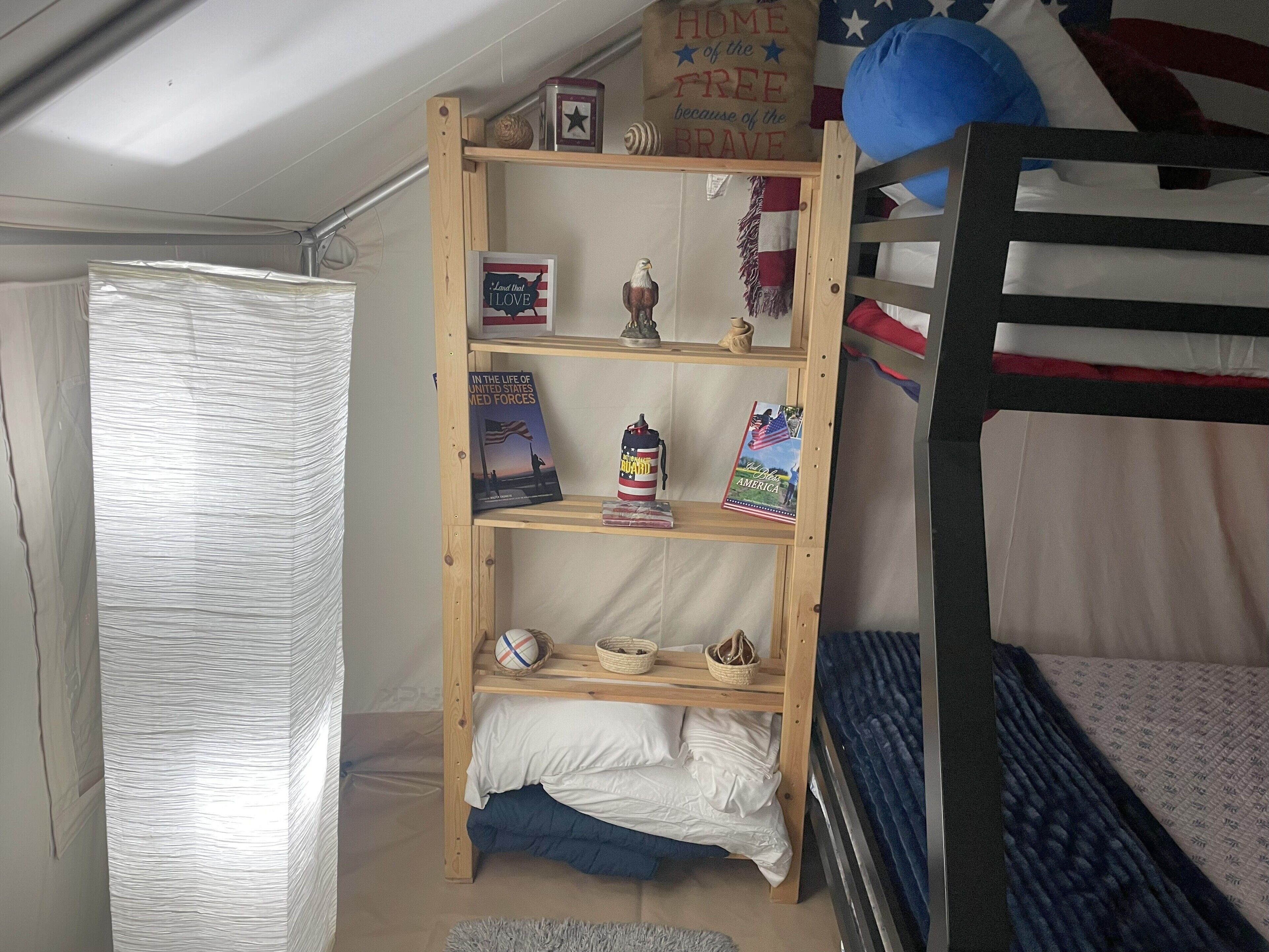 Ein Stockbett mit einem daranstehenden Holzregal, das mit Büchern und Dekoration gefüllt ist.