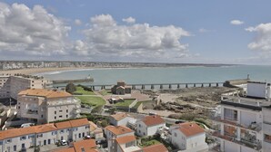 A coastal town with buildings, a beach, and a bridge.