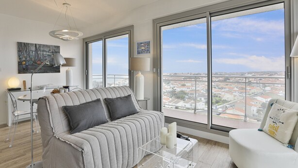 A modern living room with a large window, a sofa, a coffee table, and a chair.