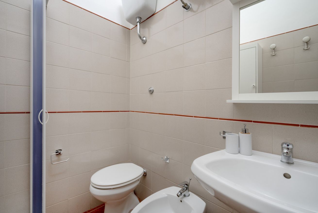 Een badkamer met toilet, bidet, wastafel en spiegel.
