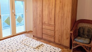 Una habitación con un armario grande de madera, una silla de mimbre y un tapete estampado en el suelo.