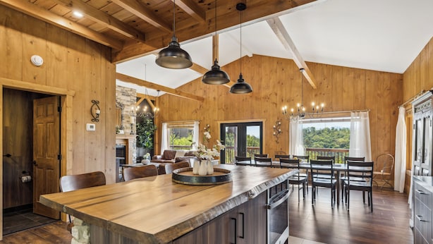 A spacious kitchen with a wooden island, pendant lights, and a view of the outdoors.