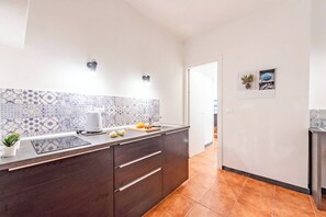 A modern kitchen with a patterned backsplash, a built-in oven, and a countertop with a kettle and fresh produce. - Yard Apartment with Balcony in Vernazza, Vernazza, Italy (Vernazza)