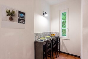 A small kitchen with a dining table, chairs, a window, and a wall-mounted light fixture.