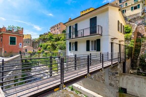 A bridge with a metal railing, connecting two buildings over a rocky terrain. - Yard Apartment with Balcony in Vernazza, Vernazza, Italy (Vernazza)