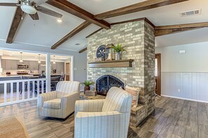 Cozy living area with a stone fireplace, ceiling fan, and striped armchairs.
