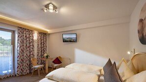 Une chambre d’hôtel avec un lit, une petite table avec des chaises, une vue sur l’extérieur par une fenêtre et un tableau au mur.