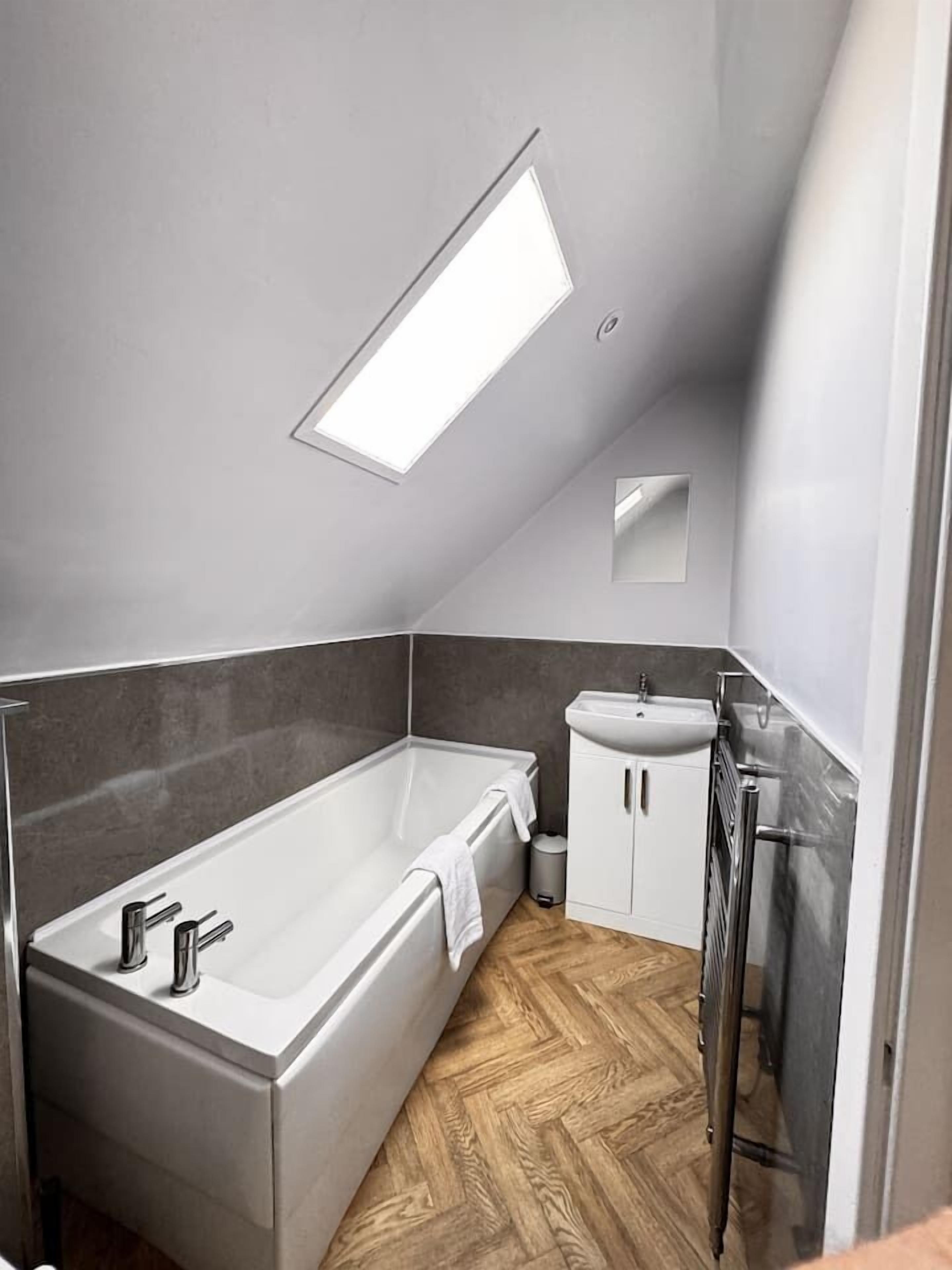 A modern bathroom with a freestanding bathtub, a pedestal sink, and a walk-in shower.