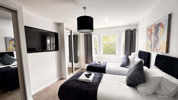 Une chambre d’hôtel moderne avec deux lits, une grande fenêtre et un téléviseur à écran plat.