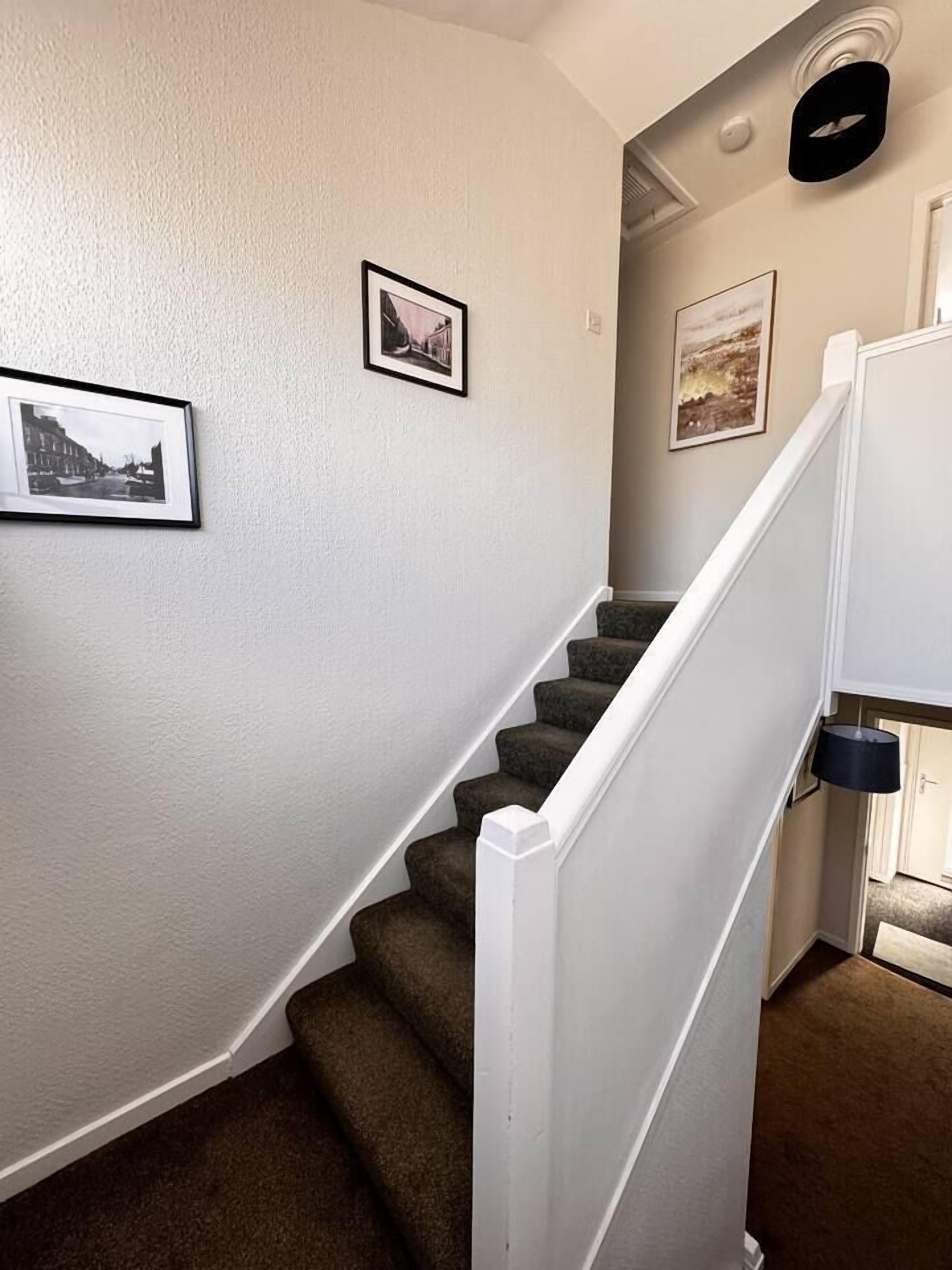 Een trap met een witte leuning en beklede treden.
