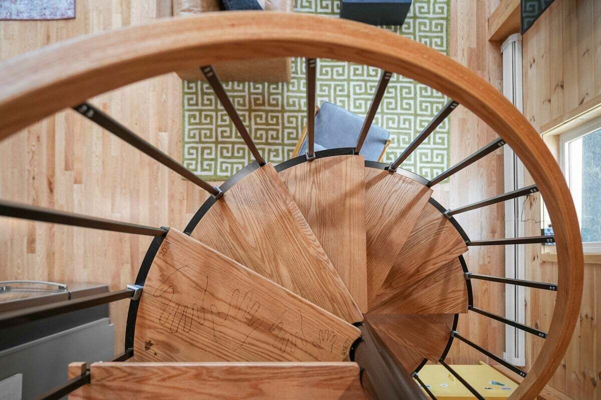 Una escala espirall de fusta amb baranes metàl·liques.