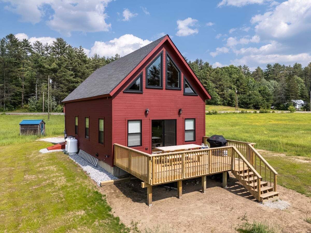 A red building with a deck, a covered outdoor area, and a staircase leading to the deck.