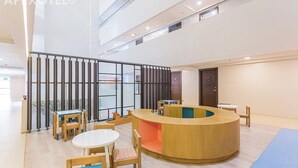 Eine moderne Hotelhalle mit Empfangstresen, Sitzgelegenheiten und Glastrennwänden.