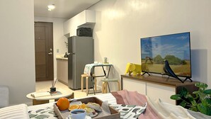 Ein kompakter Wohnbereich mit Küchenzeile, Essbereich und an der Wand montiertem Fernseher.