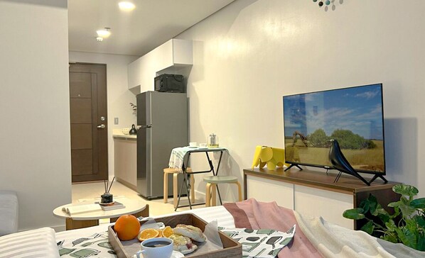 A compact living space with a kitchenette, a dining area, and a TV mounted on the wall.