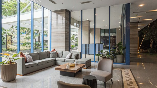 Eine moderne Lobby mit einer Eckcouch, einem Holztisch und einem Blumentopf.