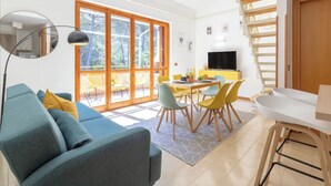 Una sala de estar moderna con sofá, mesa de comedor, sillas y televisor.