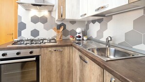 Una cocina con estufa a gas, horno, pileta de acero inoxidable y muebles de madera.