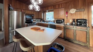 Una cucina moderna con mobili in legno, elettrodomestici in acciaio inossidabile e un'isola centrale con sgabelli.