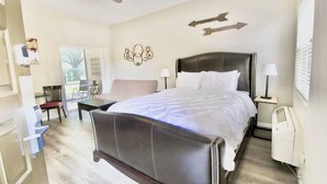 Un dormitorio con cama, mesitas de noche, ventilador de techo y vistas al exterior.