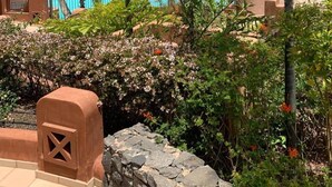 A pool area with a view of the ocean, surrounded by palm trees and other greenery. - Bahia - 2 bedroom seafront (Palm-Mar)