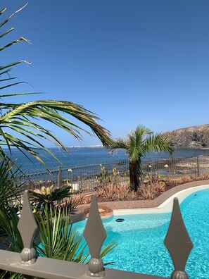 A swimming pool with a view of the sea, surrounded by palm trees and a fence. - Bahia - 2 bedroom seafront (Palm-Mar)