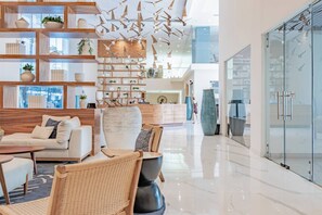 A modern interior with a sofa, chairs, a coffee table, a wooden bookshelf, and a glass wall.