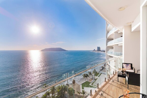 A balcony with a view of the ocean and a city skyline.