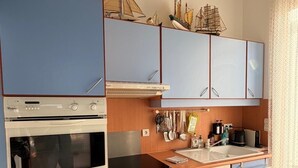 Une cuisine compacte avec des meubles bleus, un four à micro-ondes, un four traditionnel et un petit évier.