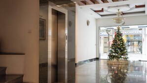 Eine Lobby mit Weihnachtsbaum, einer Kristallleuchtre und einem Restaurant im Hintergrund.