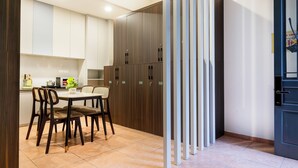 Een moderne keuken met witte kasten, een eettafel met stoelen en een deur met een zwart frame.