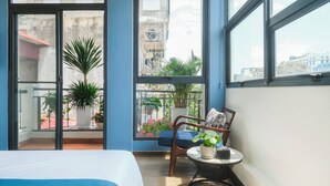 Een moderne hotelkamer met een balkon, grote ramen en uitzicht op de stad.