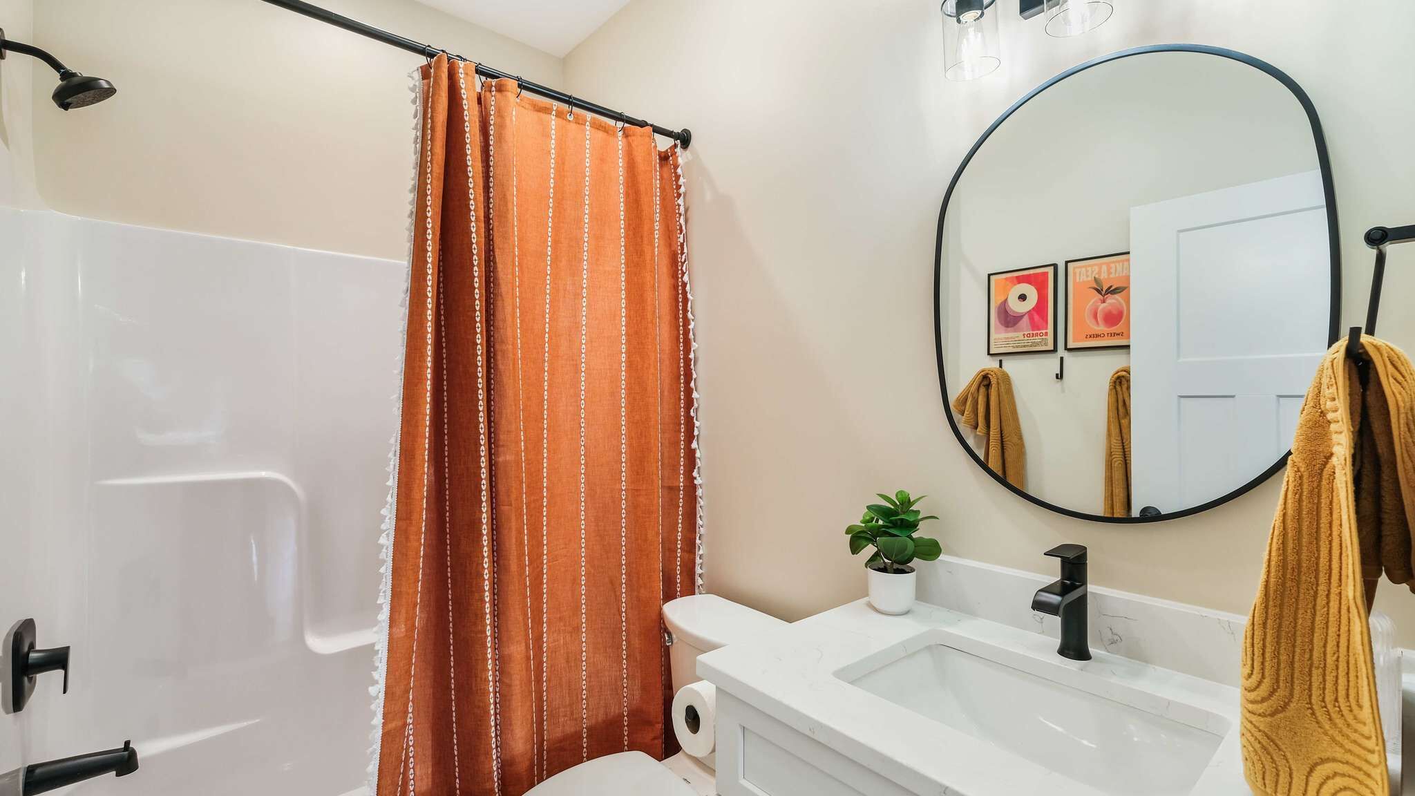 Ein Badezimmer mit Dusche, Toilette, Waschbecken und einem runden Spiegel.