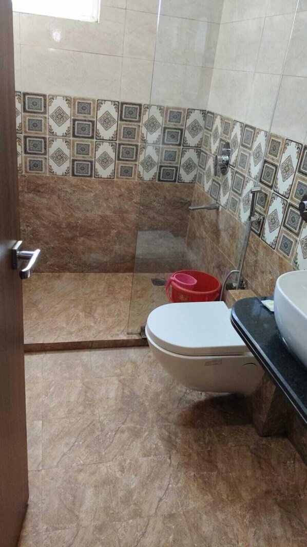 Un baño con inodoro, lavamanos y zona de ducha.