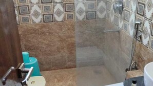 Une salle de bain avec douche, toilettes et lavabo.